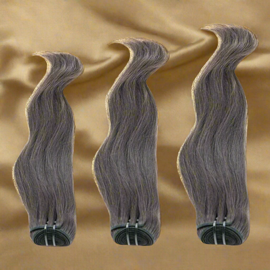 Three bundles of gray hair extensions on a beige background